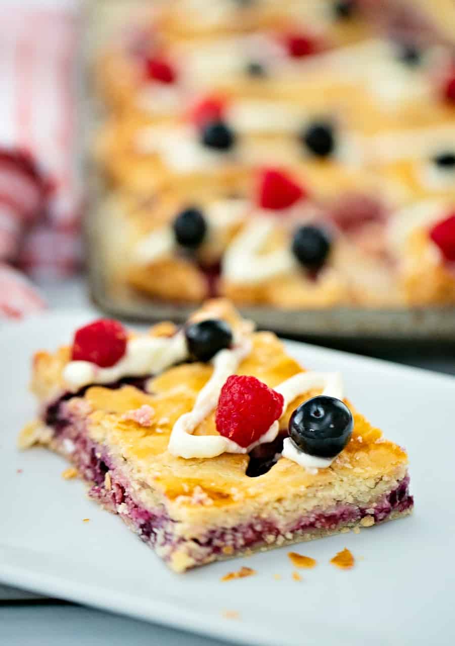 Raspberry Blueberry Slab Pie with a cream cheese frosting drizzle garnished with fresh berries. Delicious and easy patriotic dessert for Memorial Day or Fourth of July. 