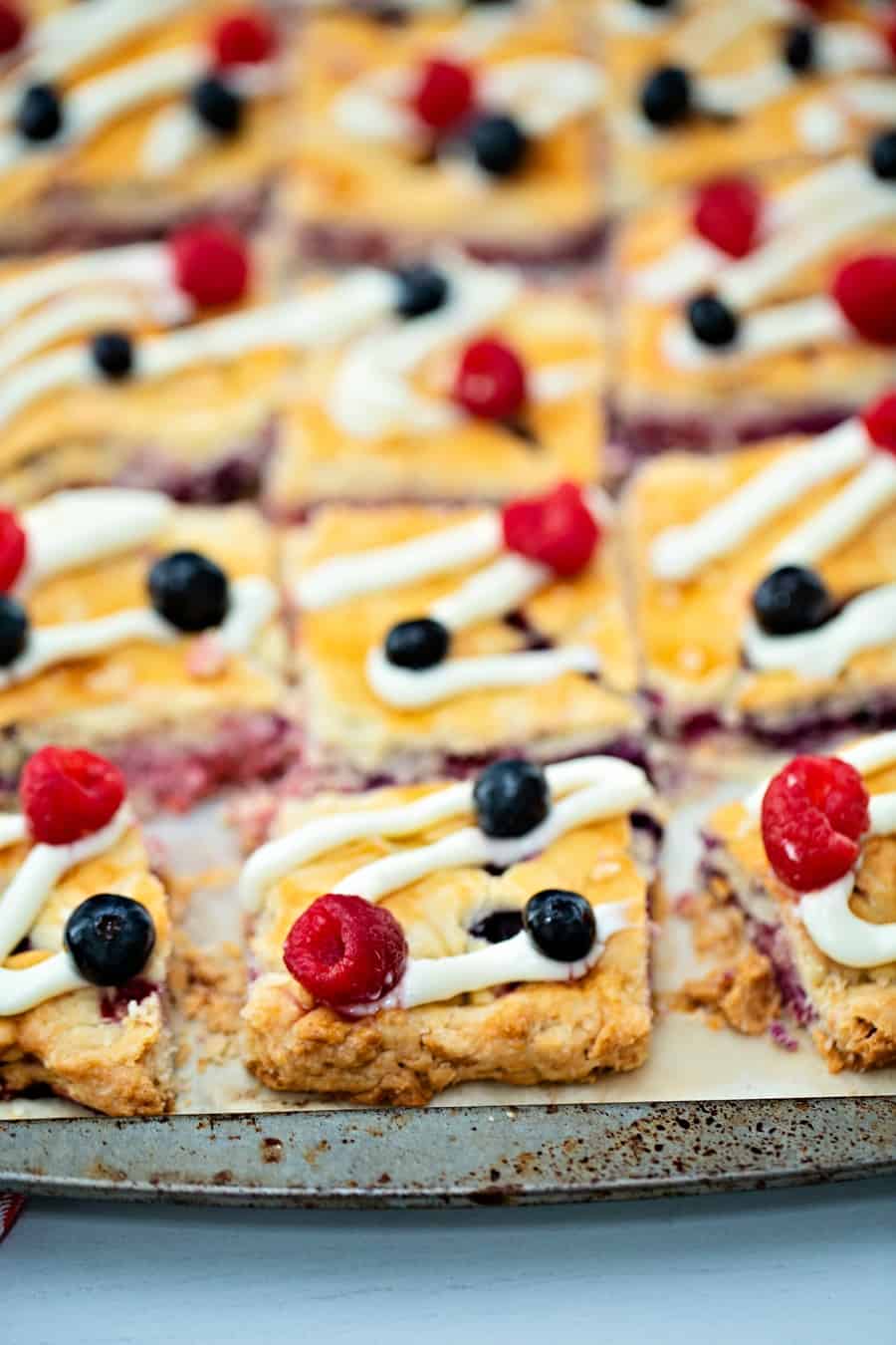 Raspberry Blueberry Slab Pie with a cream cheese frosting drizzle garnished with fresh berries. Delicious and easy patriotic dessert for Memorial Day or Fourth of July. 