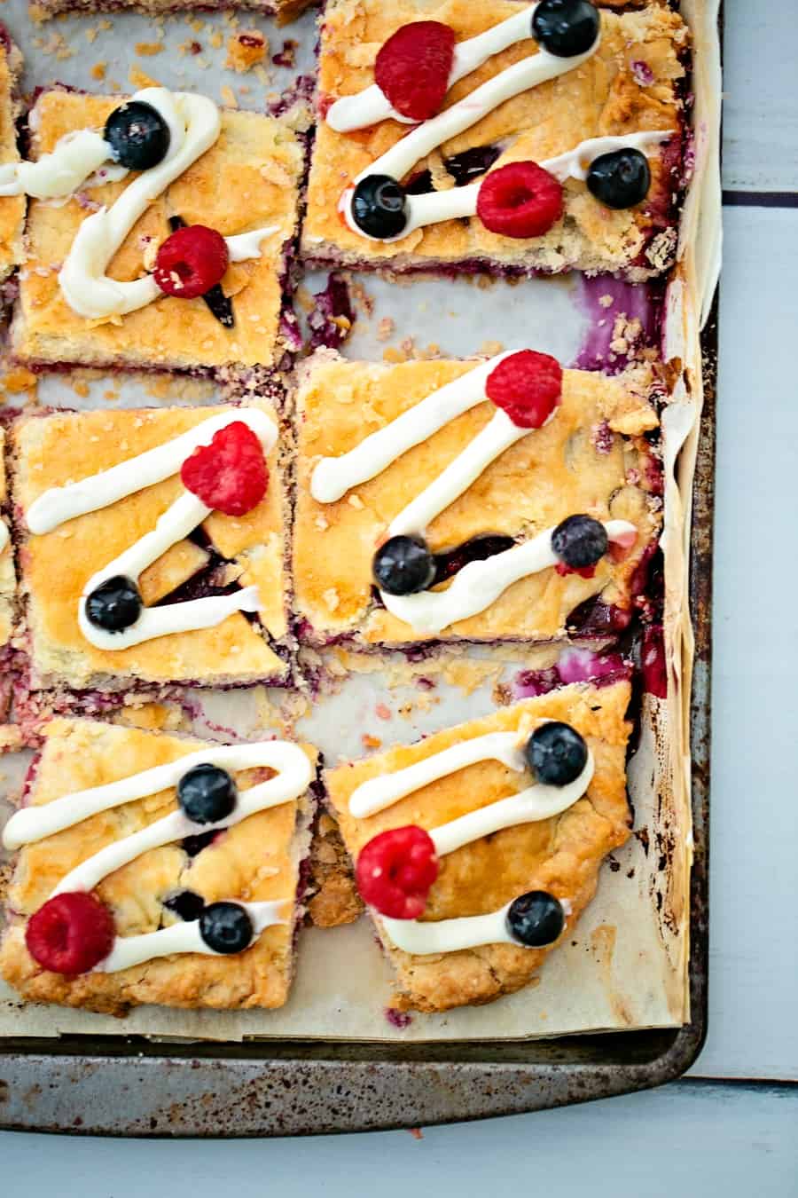 Raspberry Blueberry Slab Pie with a cream cheese frosting drizzle garnished with fresh berries. Delicious and easy patriotic dessert for Memorial Day or Fourth of July. 