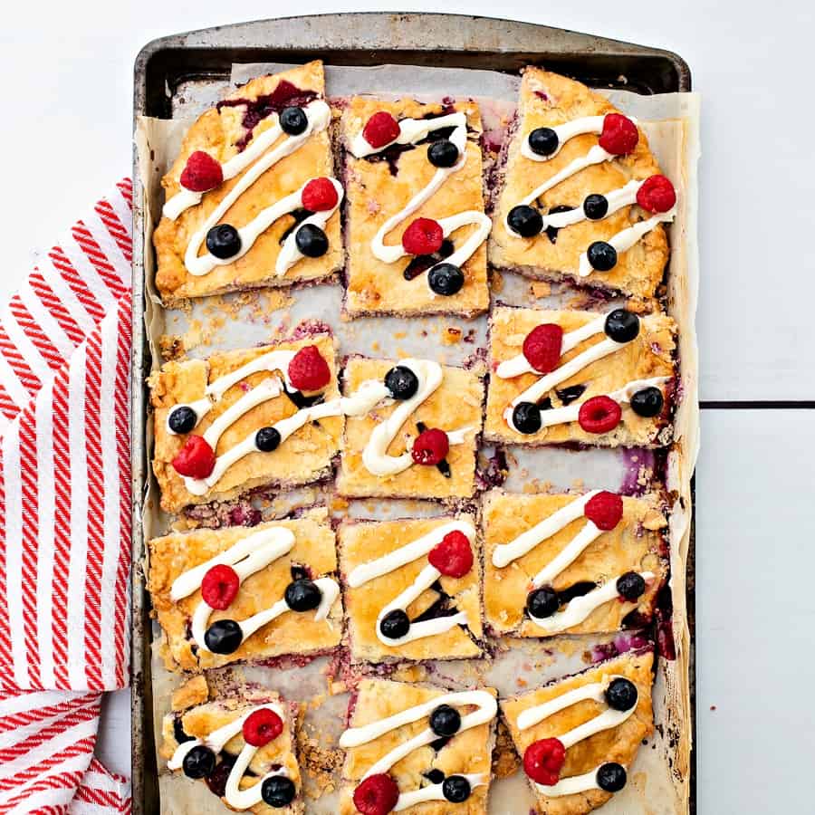 Raspberry Blueberry Slab Pie with a cream cheese frosting drizzle garnished with fresh berries. Delicious and easy patriotic dessert for Memorial Day or Fourth of July. 
