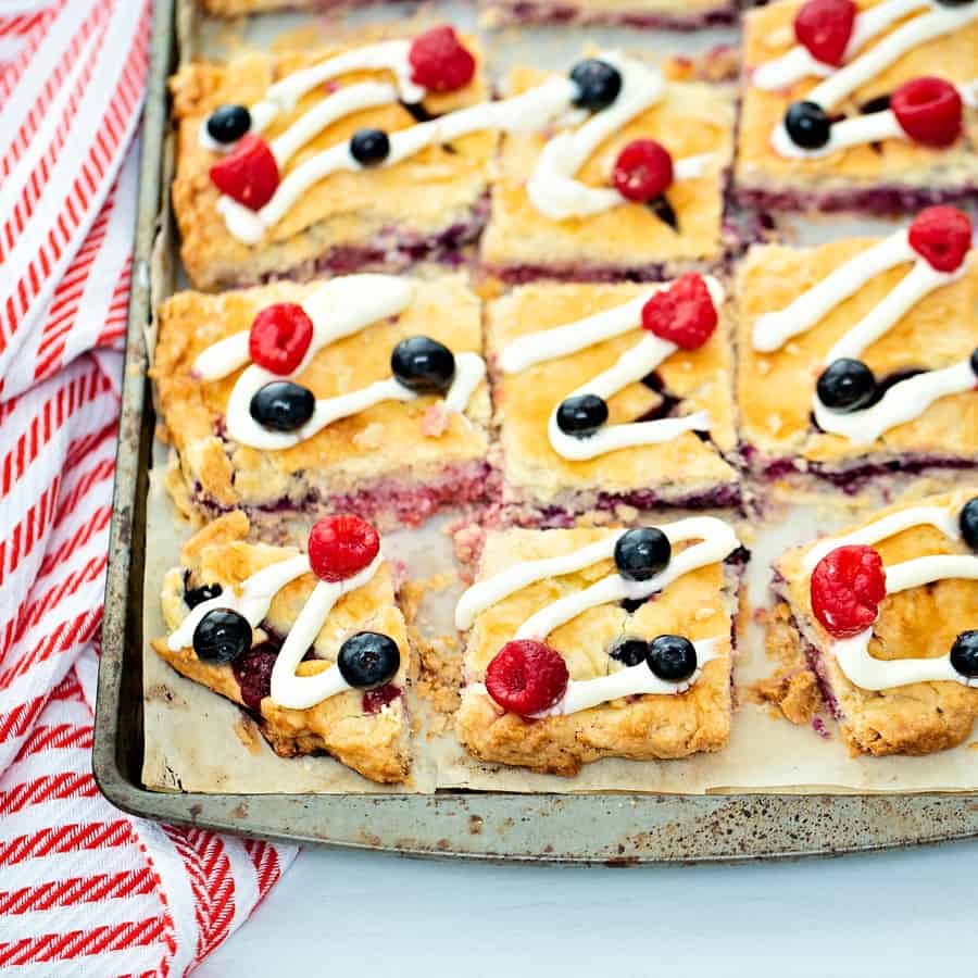 Raspberry Blueberry Slab Pie with a cream cheese frosting drizzle garnished with fresh berries. Delicious and easy patriotic dessert for Memorial Day or Fourth of July. 