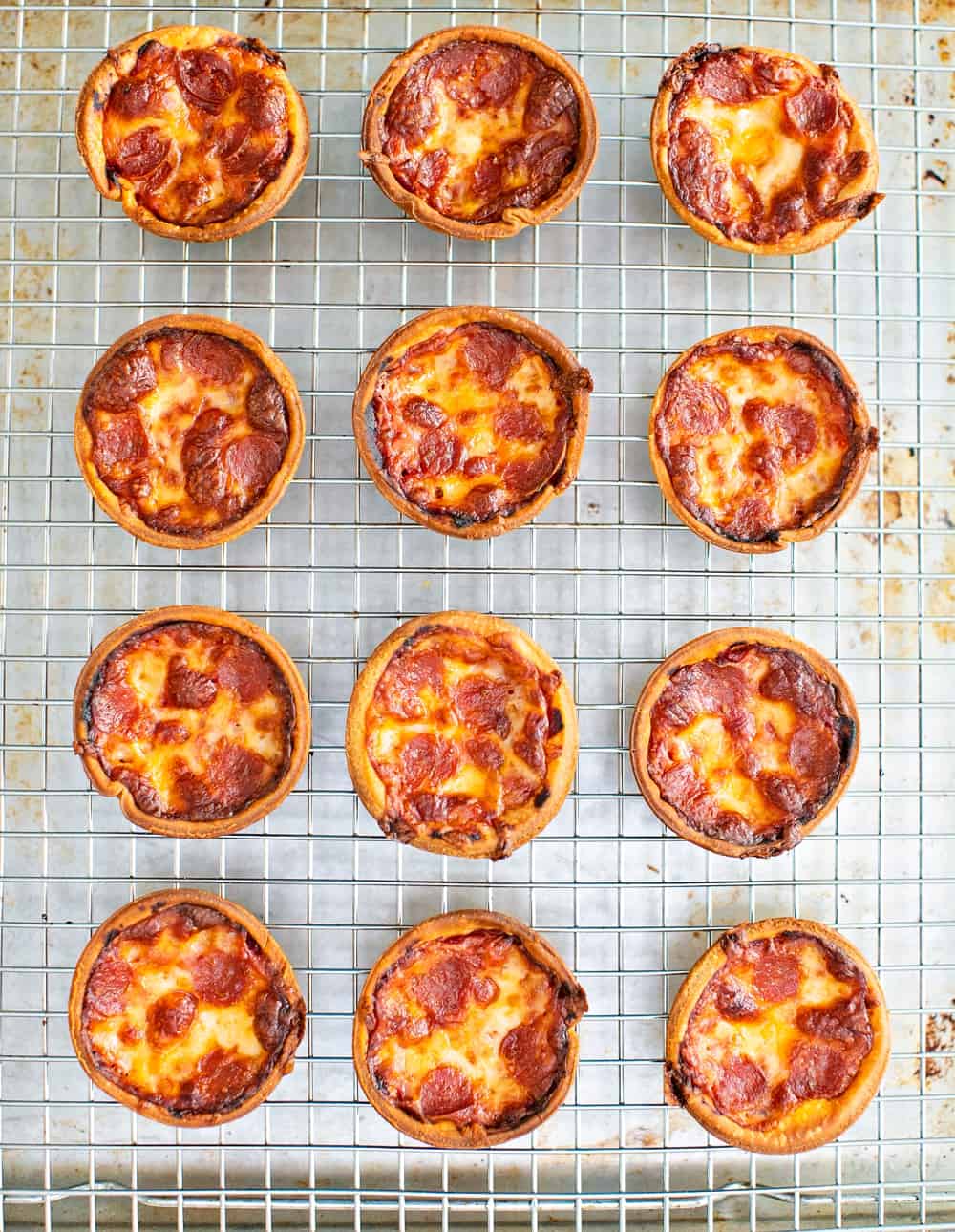 12 muffin tin pizza cooling on a baking rack 
