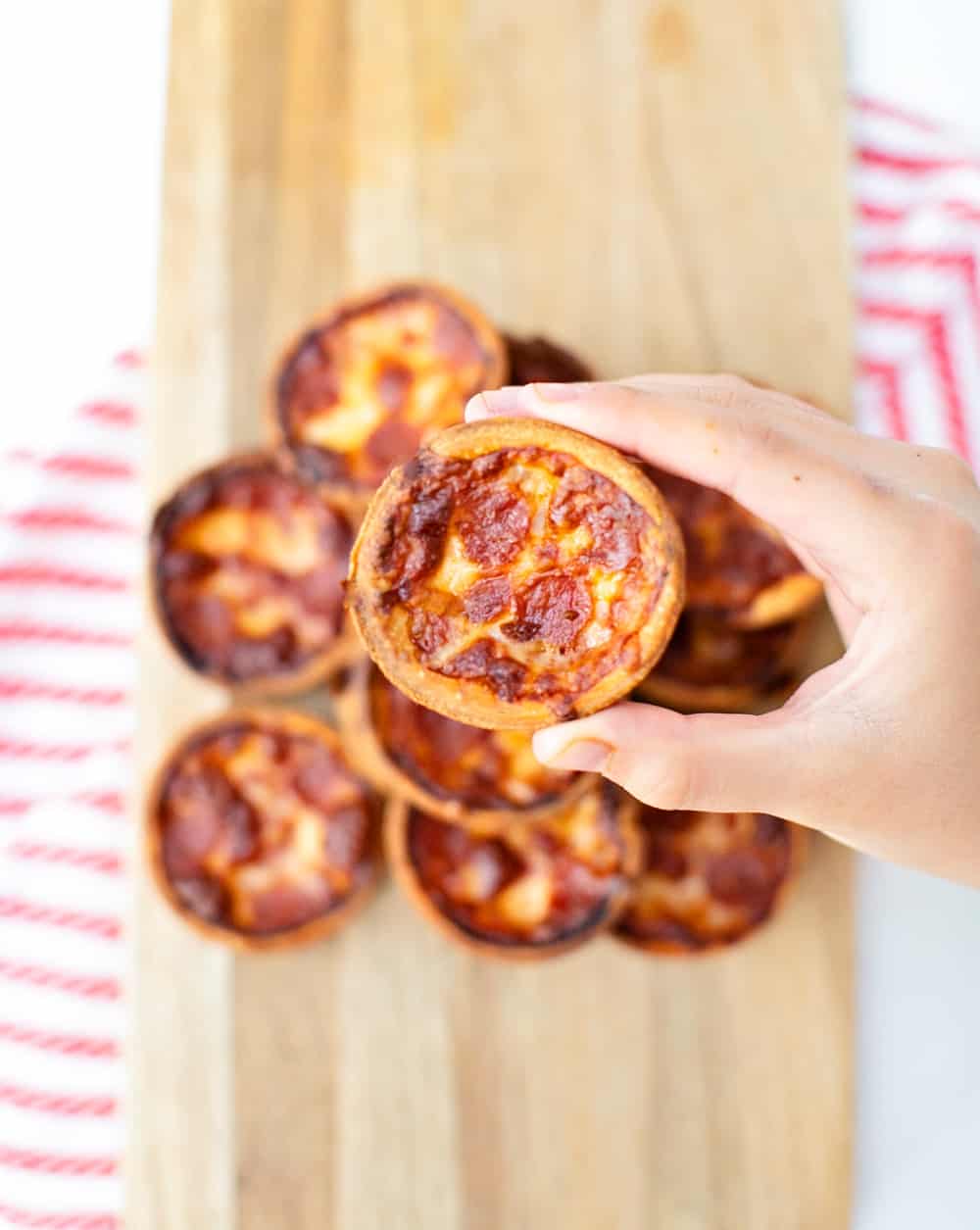 Mini muffin tin pizza one hand showing one pizza off