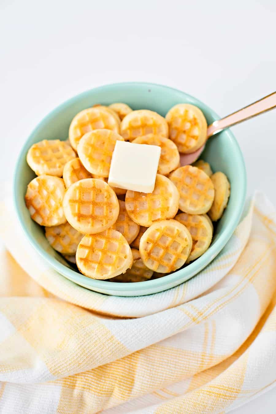 Waffle pancake cereal. Mini waffles in a bowl with a pat of butter. 