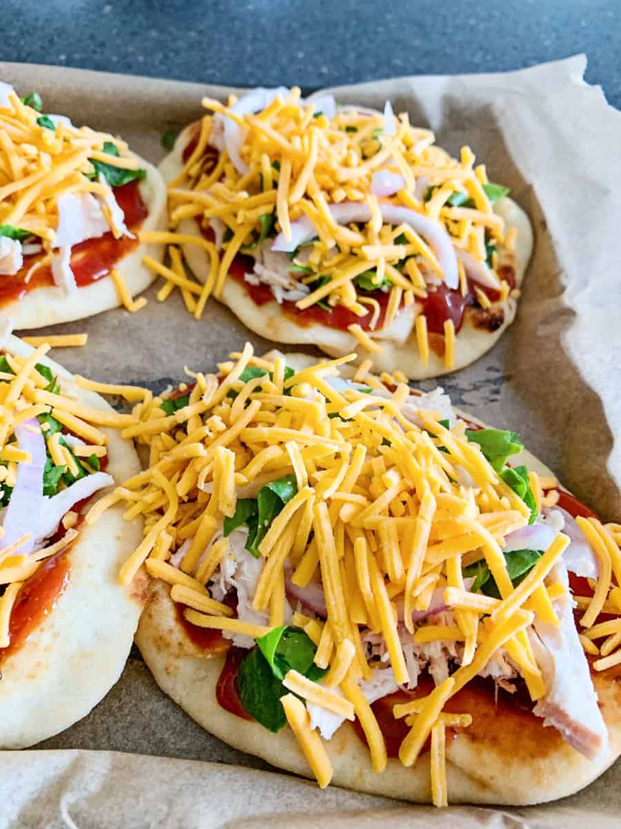 shredded cheese on top of naan bbq chicken 