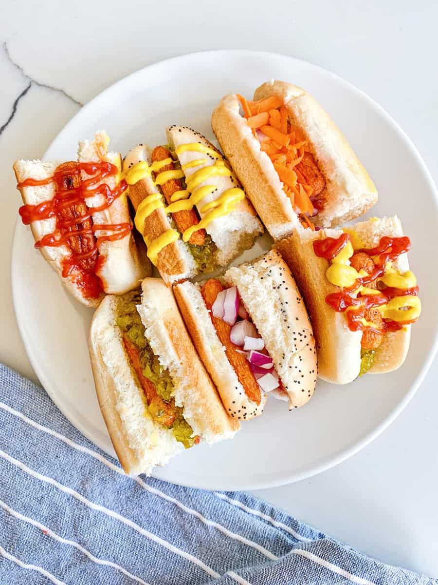 carrot hot dogs on sliced half buns with various hot dog toppings like mustard, ketchup and relish