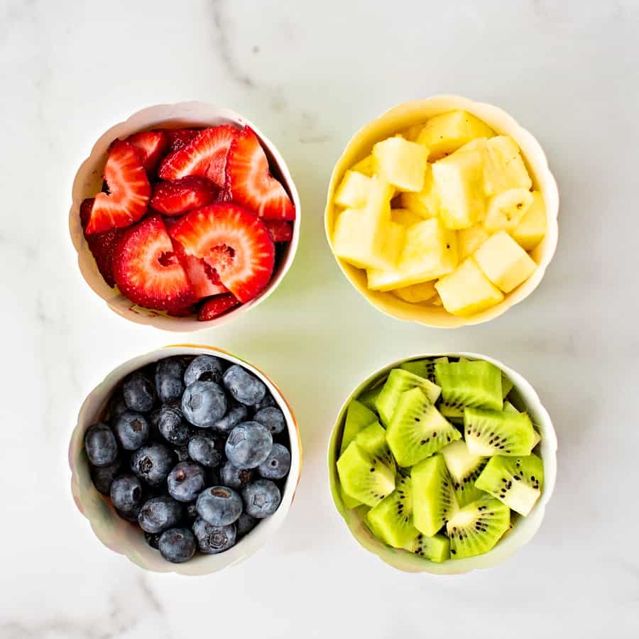 bowls of fruit blueberries, kiwi, pineapple and strawberries up up close