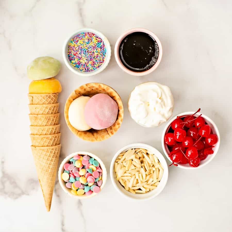 mochi ice cream on a cone with cherries and whipped cream and sprinkles