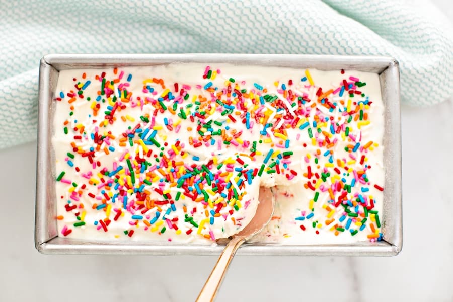 sprinkles no churn ice cream in a loaf pan with a spoon inside