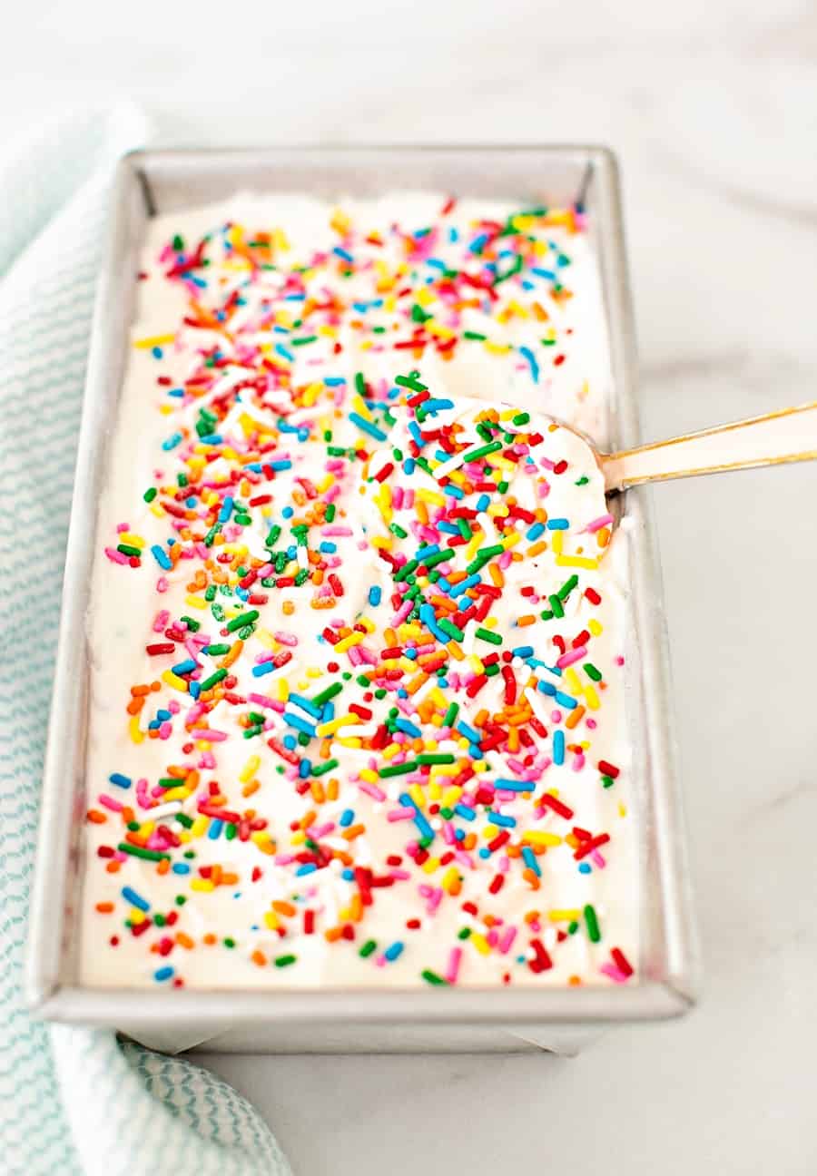 a spoon inside a loaf pan that has sprinkles ice cream