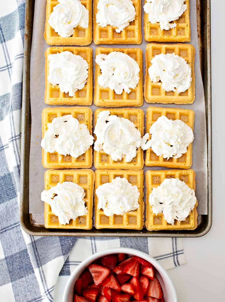 waffles on top of a sheet pan with whipped cream on top