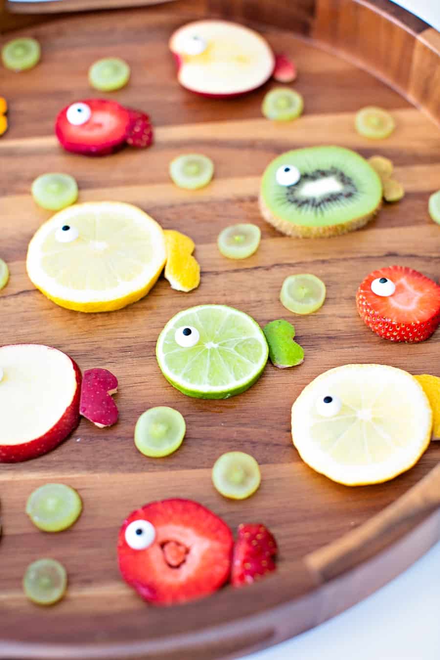 oranges, limes, kiwi and apples cut to resemble fish fruit for a kid snack 
