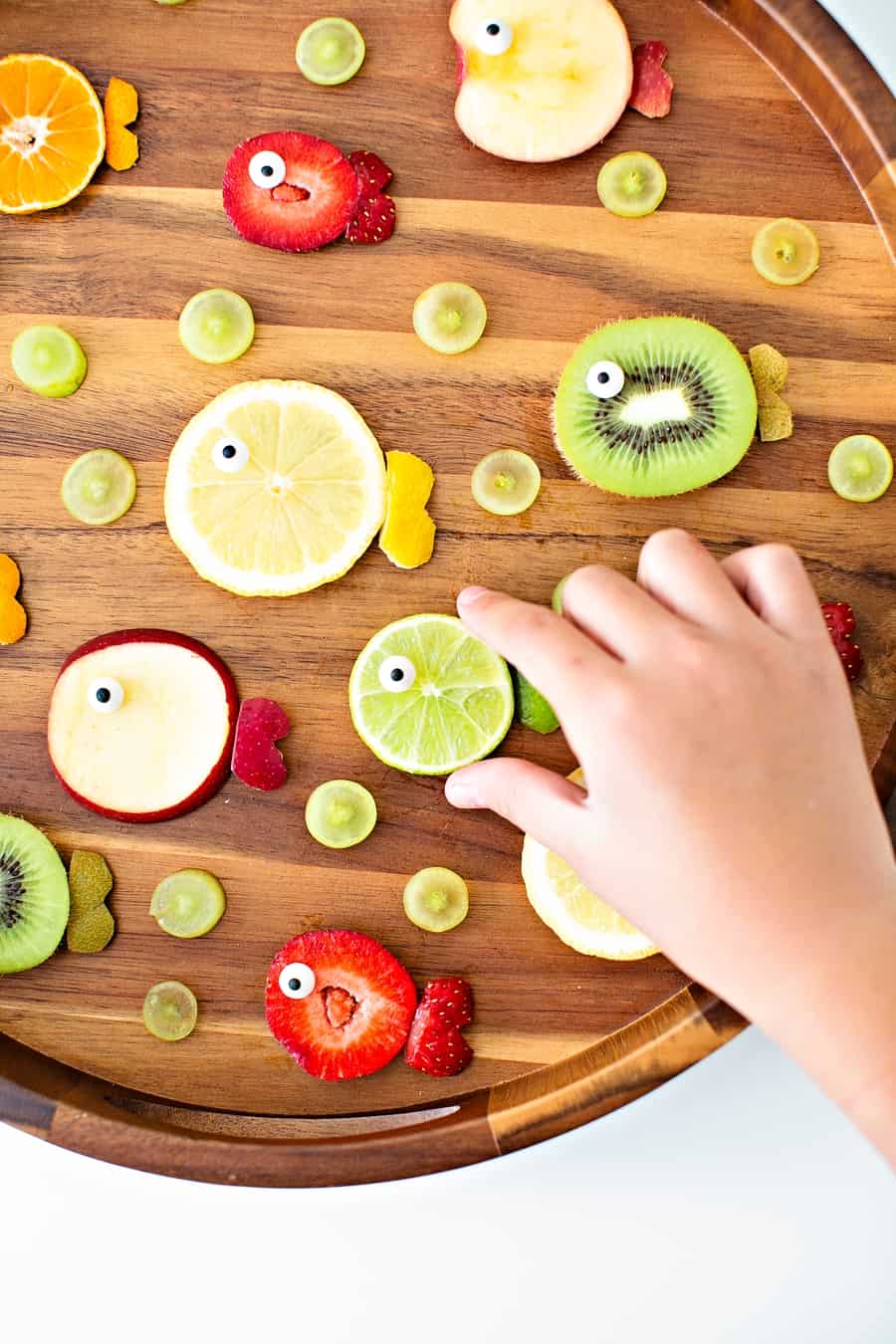 strawberries, oranges, limes, kiwi and apples cut to resemble fish fruit for a kid snack 