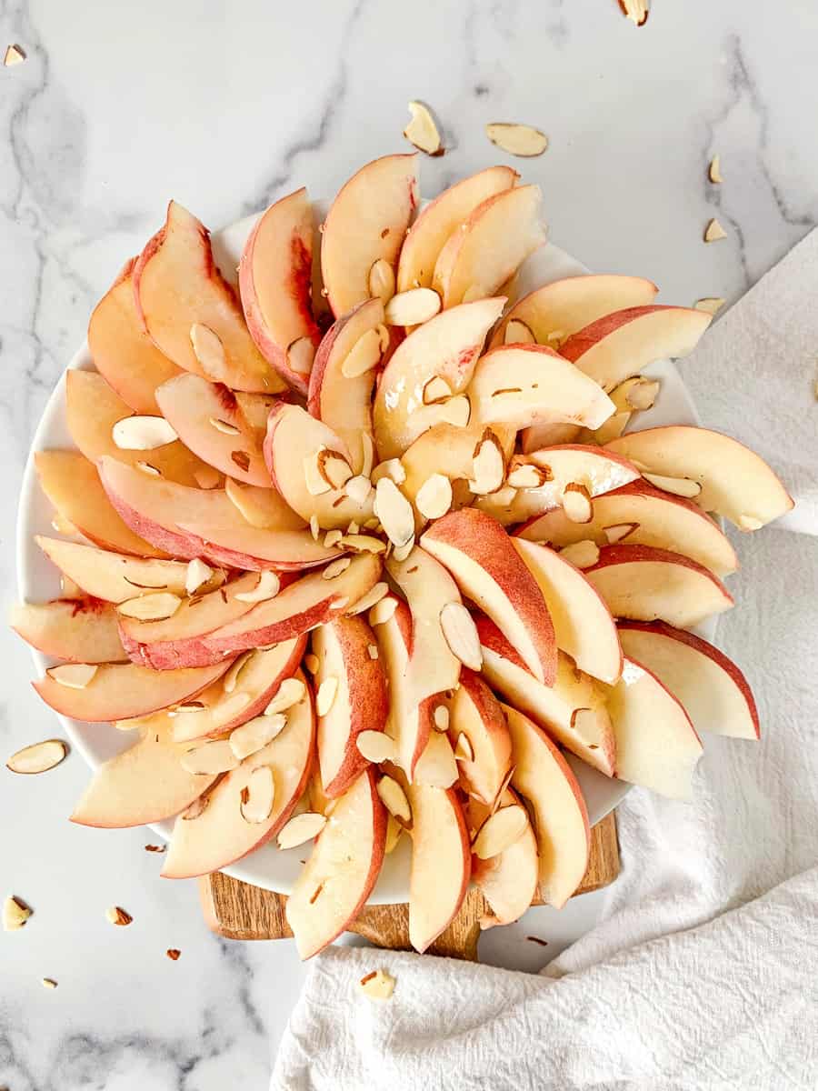 sliced peaches in a spiral to make fruit peach nachos with sliced almonds on top