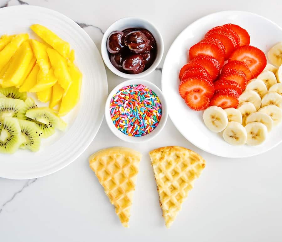 sliced fresh fruit, sprinkles and waffles cut into cones to make ice cream cone waffles