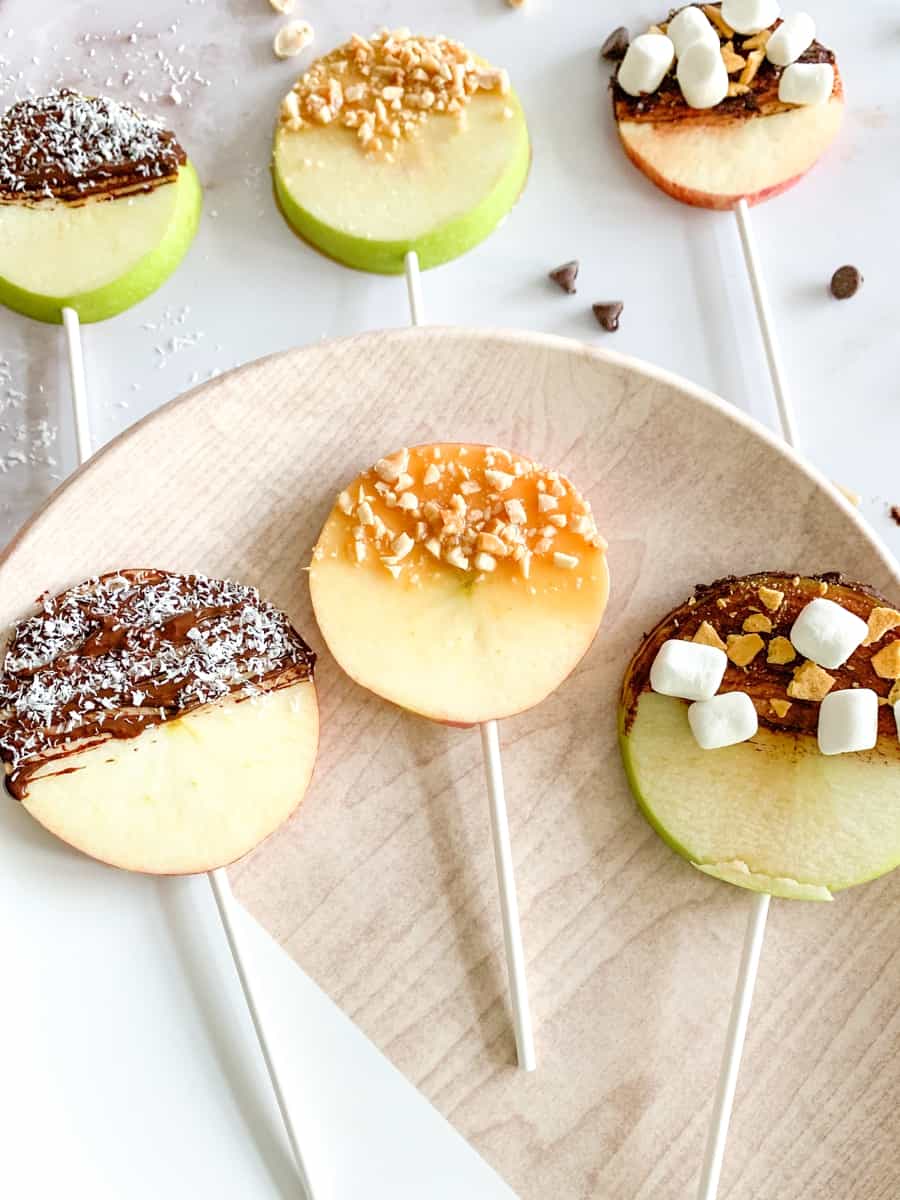 apple fruit lollipops. sliced apples with lollipop sticks and various chocolate, caramel and nut toppings