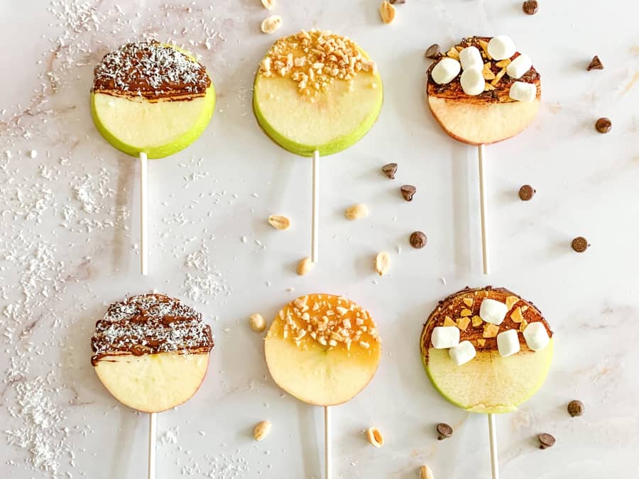 apple fruit lollipops. sliced apples with lollipop sticks and various chocolate, caramel and nut toppings